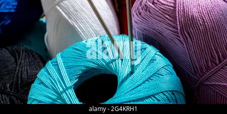 two twisted knitting needles inserted in the yarn roll, macro view Stock Photo