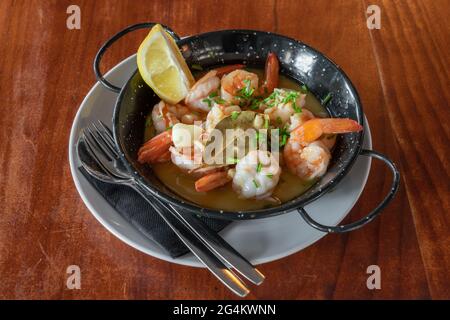 Shrimps in a metal plate stewed in sauce with a slice of lemon. Traditional Portuguese cuisine. Mediterranean Culture. Top view. Stock Photo