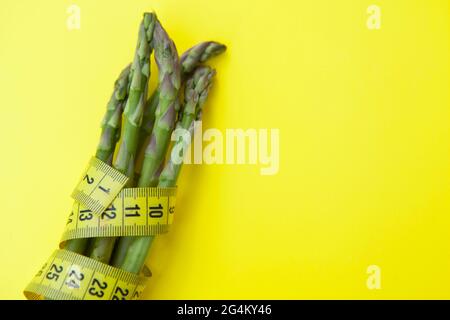 Close up of asparagus bunch wrapped in tape measure, copy space Stock Photo
