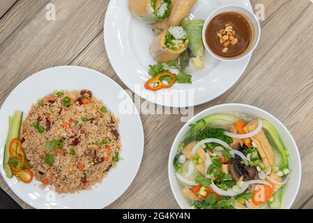 Choices of different Vietnamese tofu spring rolls, fried rice, and pho arranged on a table for presentation. Stock Photo