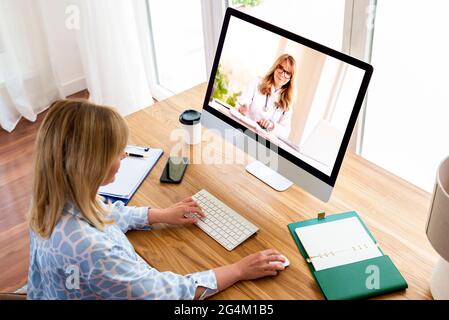 Shot of middle aged woman using a computer to make a video call with her female doctor. Stock Photo