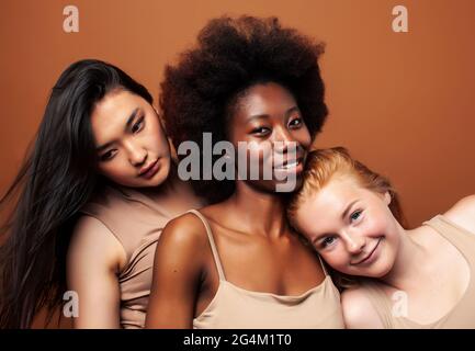 young pretty asian, caucasian, afro woman posing cheerful together on brown background, lifestyle diverse nationality people concept Stock Photo