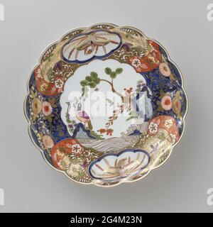 . Dish of painted porcelain. The dish is a faithful copy of an Imari example. On the flat is a bird painted on a rock and a busy decor of flowers on the edge, in which two six-spectant fields have been saved with a bird in it. The dish has been marked. Stock Photo