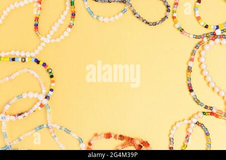 Necklaces and bracelets made from beads and pearls on a golden background. Border frame with copyspace. Stock Photo
