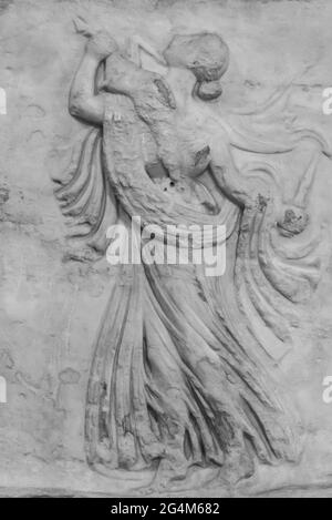 Black and white photo in close-up of ancient illustration carved on a marble wall showing a woman carrying a dead rabbit Stock Photo