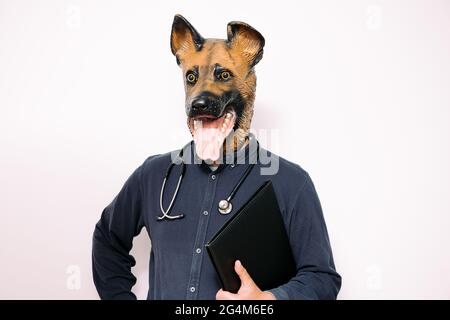 person with a dog mask and stethoscope with a folder under his arm on white background, concept of a reliable veterinary clinic for your pet Stock Photo