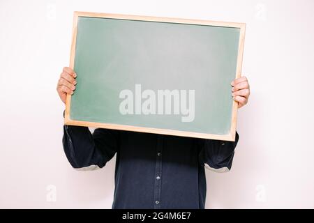 unrecognizable person holding a blank sign in front of his face on white background, copy space for text Stock Photo