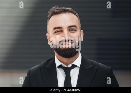 Successful business people. Happy middle-aged entrepreneur in suit standing in urban area and smiling at camera Stock Photo