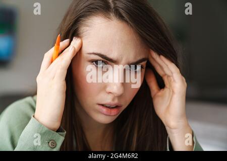 Young unhappy woman with headache rubbing her temples indoors Stock Photo