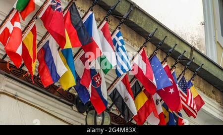 The flags of many OECD countries hang on the wall of a house in a city street. Stock Photo