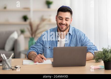 Smiling israeli man working on laptop at home Stock Photo