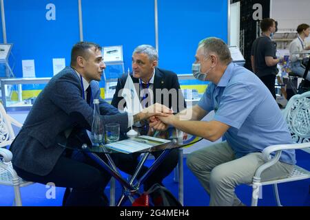 Good deal. Two businessmen shaking hands sitting at the table in the lounge zone after negotiations . Arms and Safety Exhibition. June 15, 2021. Kyiv, Stock Photo