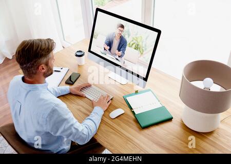 Shot of businessman sitting behind his computer and having discussion and online meeting in video call.  Business meeting online. Teamwork. Stock Photo