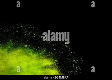 Abstract green dust splattered on black background. Freeze motion of green powder splash. Stock Photo