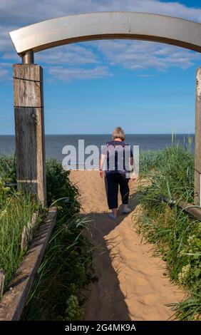 A blonde woman enjoys walking on the sandy beach on a hot summer's day in Mablethorpe, Lincolnshire Stock Photo