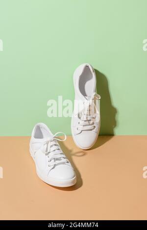 White female gumshoes on beige and green color background. Vertical format. Stock Photo