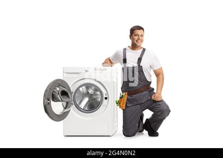 Repairman kneeling next to a washing machine and looking at camera isolated on white background Stock Photo