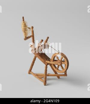 Spinning wheel, upright model on tripod. A spinning wheel, upright model of rotated and with various decoration, legs on three-legged with staircase connected to metal garland from the wheel that is in the middle between three turned styles; Upstairs, attached to these styles the coil or spindle with wing and the spin skirts. Stock Photo