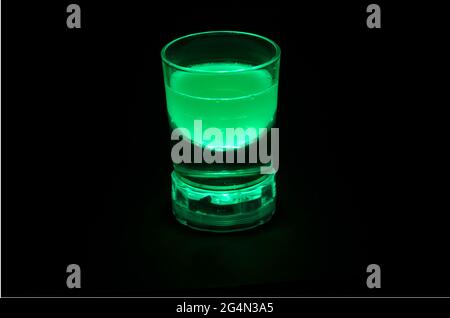 drink in a transparent glass with green backlight, green glowing drink, a glass of drink Stock Photo