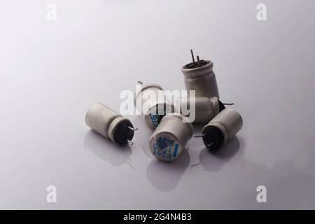 Damaged cracked electrolytic bloated exploded capacitor on white background. Minimal repair electonic technology concept. Stock Photo