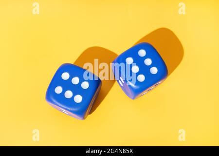 Top view of blue dice with even number of white pips on yellow background with shadows Stock Photo