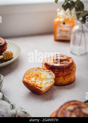 Whole and halved yummy cinnamon buns placed on table in morning at home Stock Photo