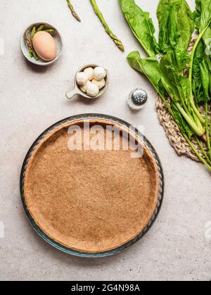 Top view of spinach and asparagus with egg and mozzarella cheese placed near pastry base for quiche preparation Stock Photo