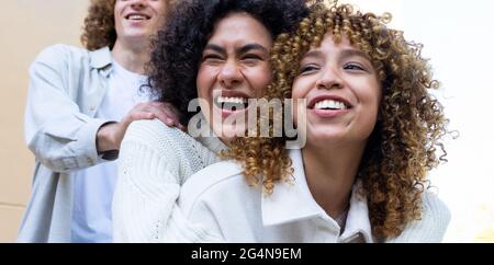 Diverse man and women standing behind each other showing heads with curly hair and laughing Stock Photo