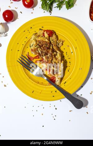 Delicious omelette with chopped parsley on plate against sun dried tomatoes on white background Stock Photo