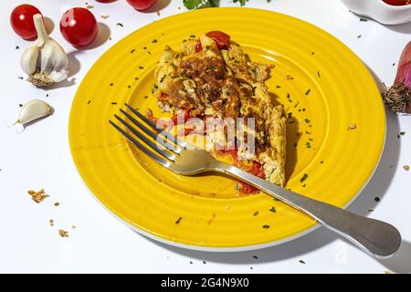 Delicious omelette with chopped parsley on plate against sun dried tomatoes on white background Stock Photo