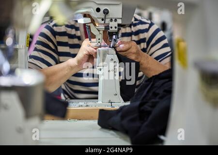 Detail of worker's hands doing sewing in the leather of the shoes at Chinese shoes factory Stock Photo