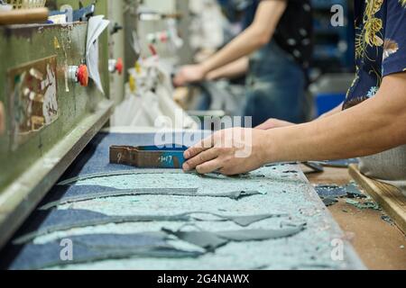 Detail of worker using of cutting pattern while cutting fabric in Chinese shoes factory Stock Photo