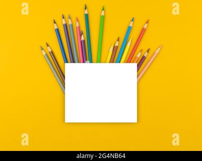 Back to school mockup, creative flat lay composition with color pencils and blank white paper on the yellow desktop table, top view and copy space Stock Photo