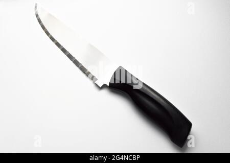 Very sharp serrated chrome metal knife with plastic handle, isolated on white background Stock Photo