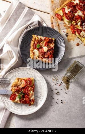 Homemade French open pie quiche with zucchini, tomatoes, mozzarella and bacon. Stock Photo