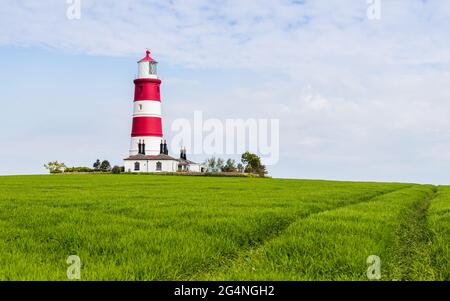 The red and white Happisburgh lighthouse on top of a hill on the North Norfolk coast pictured in June 2021. Stock Photo