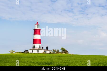 Happisburgh lighthouse under a blue sky on the Norfolk coastline pictured in June 2021. Stock Photo