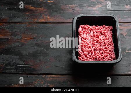 Fresh minced meat in plastic box packaging tray set, on old dark wooden table background, with copy space for text Stock Photo