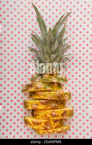 Sliced pineapple on color pink summer background. Tropical fruit Sliced pineapple rings. Creative flat lay composition on dots pink white pattern Stock Photo