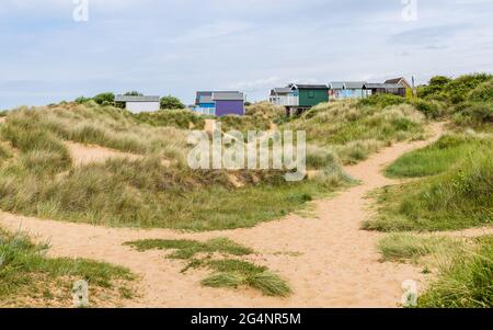 Beach huts nestled between sand dunes at Old Hunstanton on the North Norfolk coast. Stock Photo