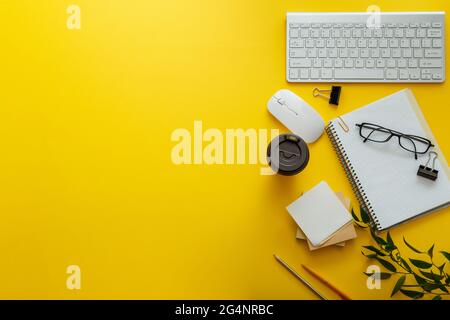 Work space desk layout with note pc keyboard coffee cup glasses bright color yellow background copy space. Modern office desk workspace flat lay Stock Photo