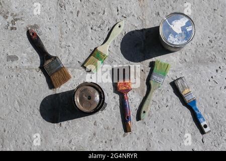 Dirty brushes and paint cans on concrete. Stock Photo