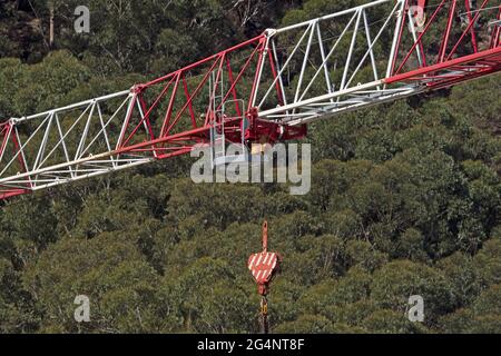 May 18, 2021. Tower crane boom and hook close up on the building construction site at 56-58 Beane St. with a green bushland background. Gosford, Austr Stock Photo