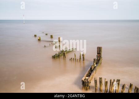 Zig zag groyne at Hunstanton beach juts out into The Wash at high tide on the North Norfolk coast. Stock Photo