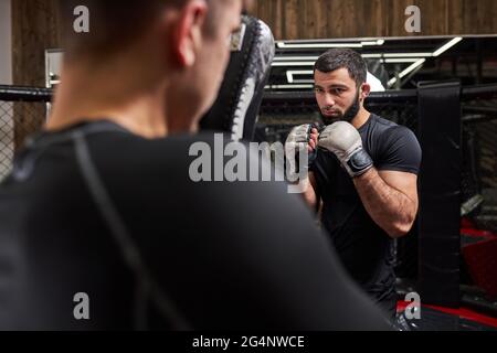 Strong Confident Fighter or Wrestler Training With Professional MMA Fighter At Gym In Ring, Preparing For Competition Together. Rear View on Man Stock Photo