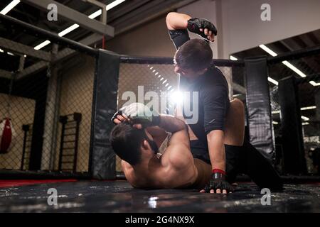 muscular MMA boxers fighters fight in fights without rules in ring octagons. Mixed martial artists during fight. sport and boxing concept Stock Photo