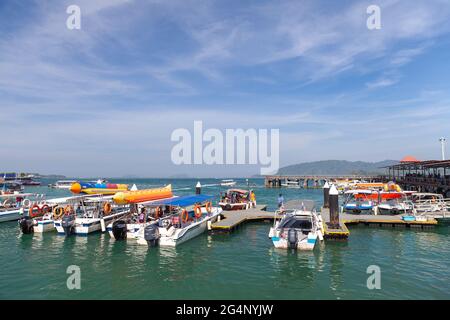 Kota Kinabalu, Malaysia - March 17, 2019: Small motorboats with passengers are near Jesselton Point ferry terminal at sunny day Stock Photo