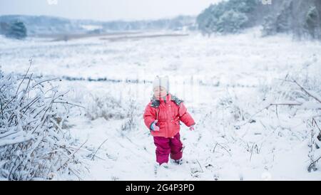 little girl throws snowball. child plays in winter outside in snow. Stock Photo