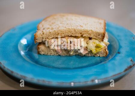 Half of a tuna fish sandwich with oatnut bread on a blue plate. Closeup. Stock Photo