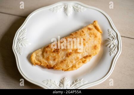 Homemade fried apple pie made from dried apples with flaky pie crust on a white plate. Stock Photo